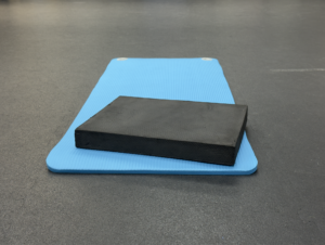 Blue yoga mat with black foam block used in Kinstretch mobility training at Omni Wellness & Performance in Fairfax, VA
